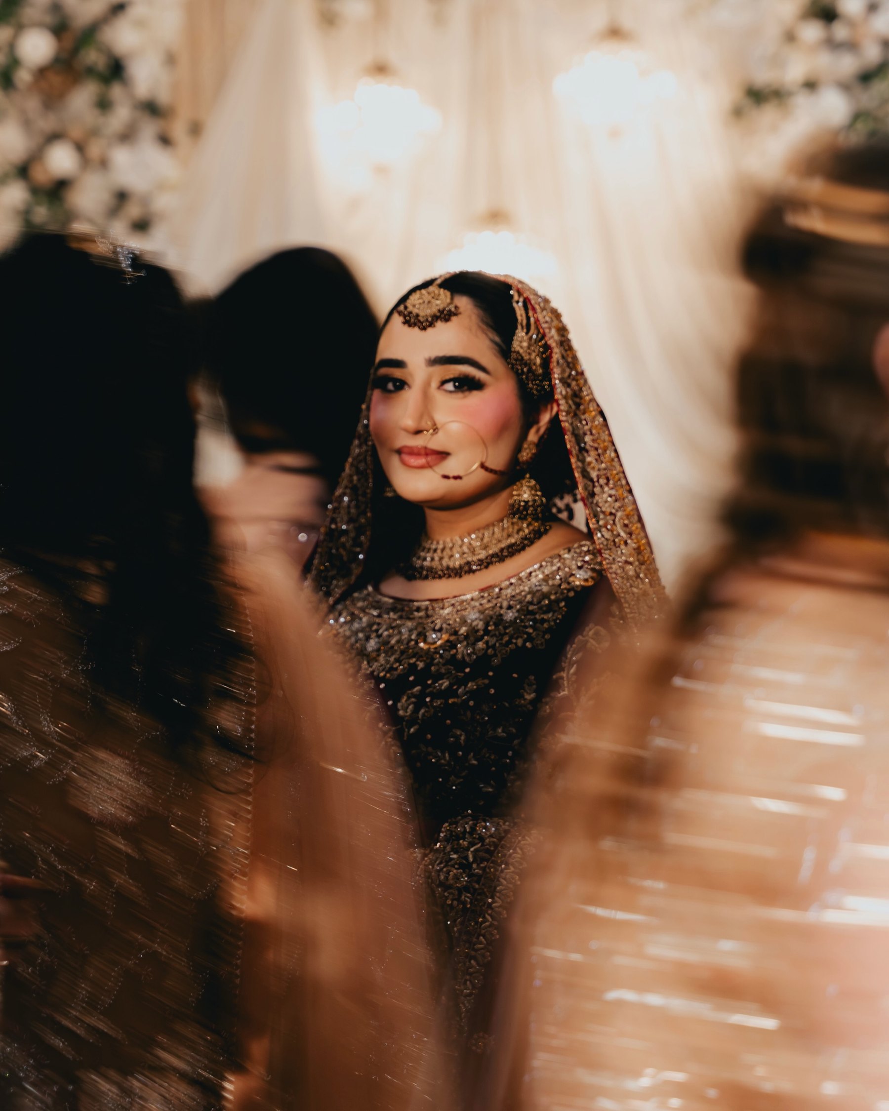 A bride in maroon and gold glimpsed between guests as they move past