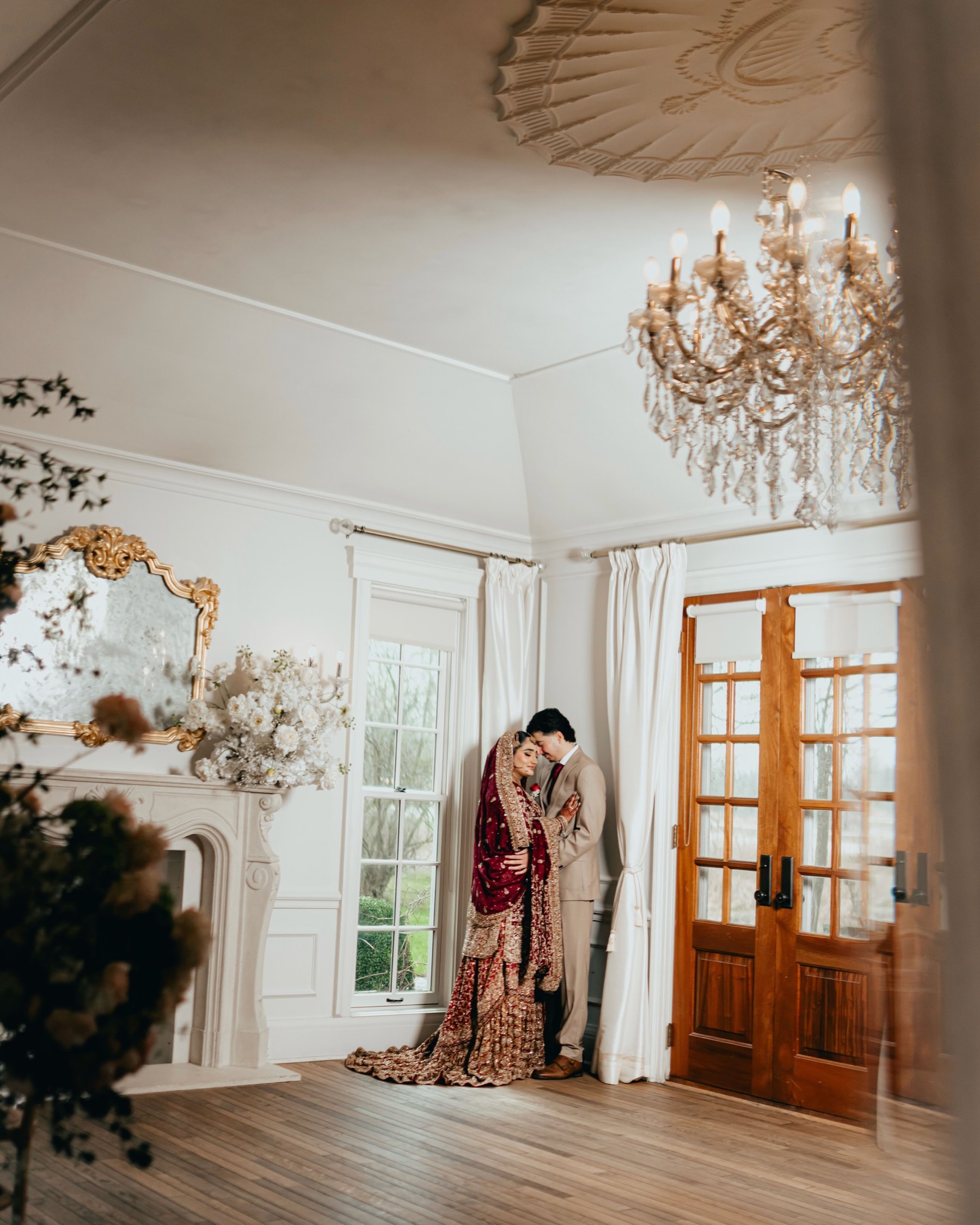 A couple share a quiet moment in a white room under a crystal chandelier